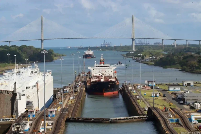Cargo ships moving through the Panama Canal locks beneath the Atlantic Bridge in Panama.
