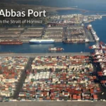 Aerial view of Bandar Abbas Port showing container yards, cranes, cargo ships, and terminal basins on Iran’s Strait of Hormuz coast.