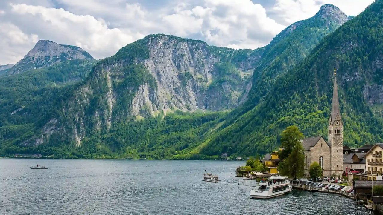 Hallstatt village and passenger boats beside Lake Hallstatt beneath steep Alpine mountains in Upper Austria.