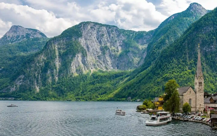 Hallstatt village and passenger boats beside Lake Hallstatt beneath steep Alpine mountains in Upper Austria.