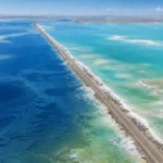 Aerial view of G315 dividing deep-blue and turquoise-green water at Xitai Jinaier Lake in Qinghai’s Qaidam Basin.