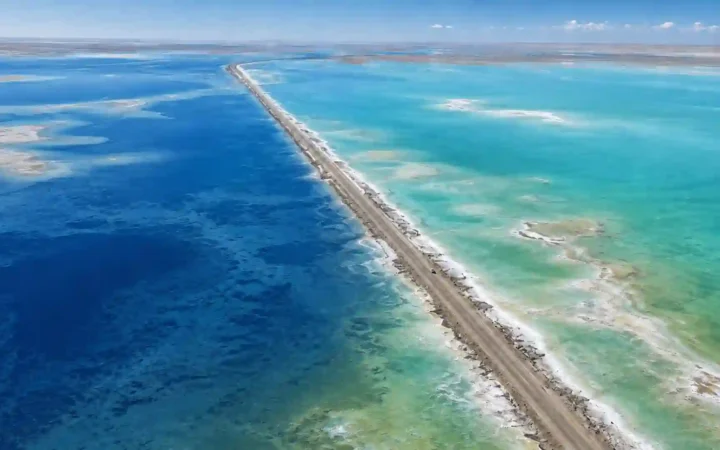 Aerial view of G315 dividing deep-blue and turquoise-green water at Xitai Jinaier Lake in Qinghai’s Qaidam Basin.